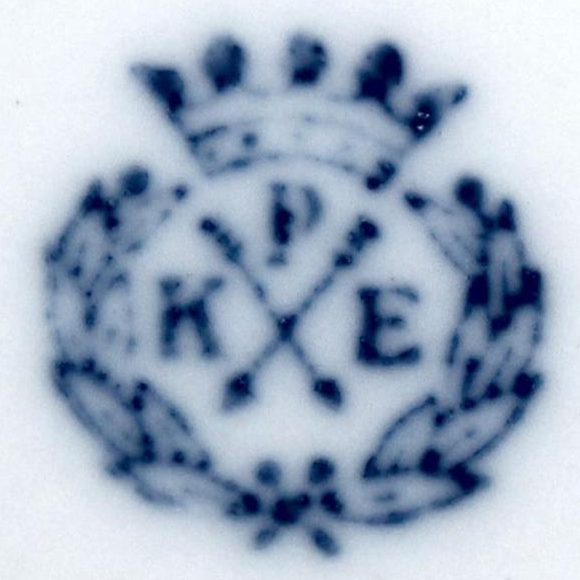 spitzwinkelig gekreuzte Pfeile, oben P, links K und rechts E, rund umkränzt, darüber Krone